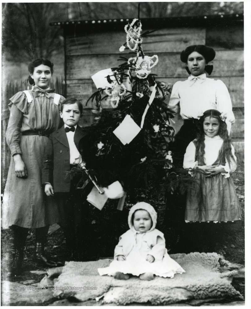 Baby Charles R. Shock seated in front of tree.  Bess and Herbert Shock standing to left of the tree.  Alma and Cinderilla (born August 30, 1901 and died June 3, 1991) Shock standing on right side of tree.