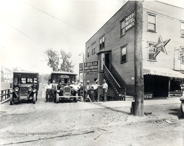 Exterior of Star Bus Company featuring employees posing for portrait with two buses; routes to Cassville and Maidsville are advertised; company office and the "Reed Hotel Annex" are in same building.<br />