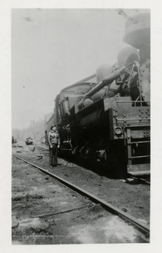 Front view of Shay train engine.  Man standing beside of it.  
