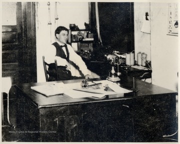 The late Fred Smith sitting at a desk.