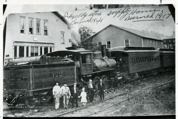 Group of men and child pose in front of train No. 122 at Lochgelly station. Left is the Lochgelly store which burned in  1941. Right is the Supply House which burned in 1917.