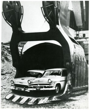 A large scoop with two cars fitting between its jaws.