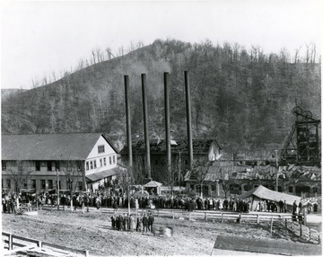 Crowds gather outside mine buildings after an explosion.