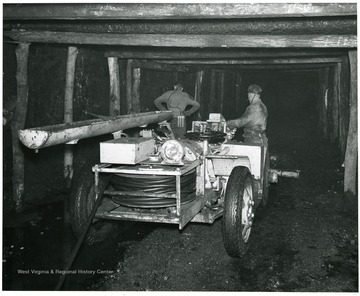Two miners standing next to drilling machine.