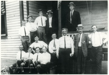 Portrait of men standing on and around a porch.