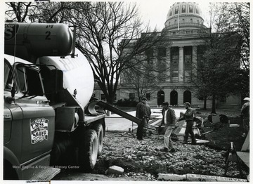 Workers lay concrete outside the capitol building.