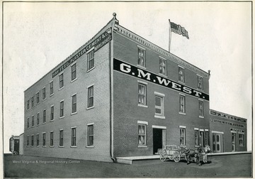 Image from 'Industrial and Picturesque Clarksburg, W. Va.' published by the Press of the Clarksburg Telegram Company, Printers and Publishers, Clarksburg, W. Va., 1911. G. M. West Warehouse for Hay, Grain, Feed, Plaster, Cement, etc. 