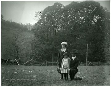 Olga Aegerter Holtkamp, Benjamin Holtkamp, and a young girl standing in fenced in field area in Helvetia, W. Va.