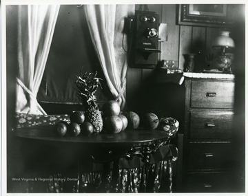 A pineapple and other round fruit are sitting on a table near a dresser and a phone in a home in Helvetia, West Virginia.