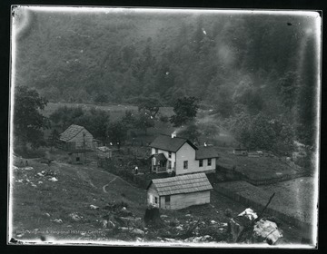 Three people are standing on a front walk of a farm house in Helvetia, West Virginia. The house is surrounded by several other farm buildings.