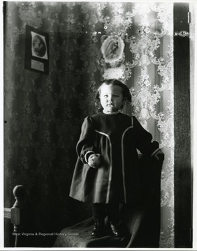 A young child is standing on a chair in a room in a house in Helvetia, West Virginia.
