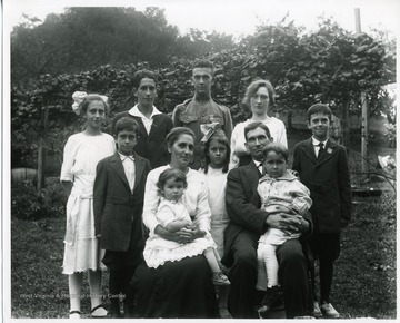 'The family of George and Bertha Teuscher Sutton. Left to right-Ida, Bill, Harley, Anna, Dave. Center row, Francis, Elda. Seated, Bertha with daughter Mable and George with son Edward. Taken on the occasion of Anna's birthday, October 07, 1918.'