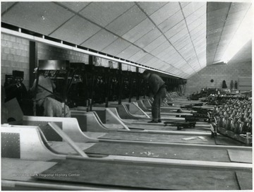 Men put the bowling alley equipment in place. 'Suburban Lanes?'