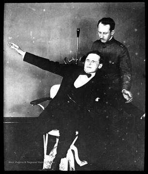 World War I Lantern Slide Show. Slide No. 04 in group of originally numbered slides. Physical examination of a recruit sitting in a chair. This is apparently a balance test for a potential pilot. Frame is labeled with text saying 'Visual Bureau, University of Pittsburgh.'  (negative no. 4-8244 is inscribed on slide)
