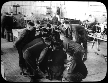 World War I Lantern Slide Show. Slide No. 09 in group of originally numbered slides.  Group of soldiers apparently learning about engine mechanics.  Frame is labelled with text saying 'Visual Bureau, University of Pittsburgh.'  (negative no. 9-450 is inscribed on slide)<br />