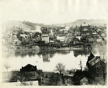 'View of Morgantown from the west side; Walnut Street Wharf; Old Firehouse in the upper end of Walnut Street, from the picture of the Wool Market was most likely made; Tower of Monongalia Academy at the left of the Firehouse. The negative for this picture was made by John L. Johnston, probably in 1892 or soon after. This twenty percent enlargement was made by F.A. Molby from the old negative (1939).'