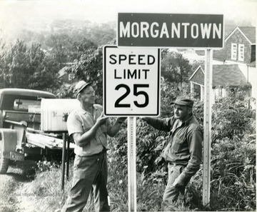 Mr. Smith (left) and Harry Franks (right) putting up a speed limit 25 sign on College Avenue.