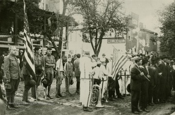 Scene of World War I draftees preparing to leave for training camp. 'This photo is from the original glass plate by M. Alexander. It was taken on Main Street near South Branch Valley National Bank. From left to right: Dr. R. E. L. Hackney, Scout Master, Frank McNeill, Boyd McWhorter, George Finley, and the boy in the white uniform with his back to the camera is Willie Dasher.'