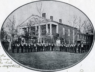 Group portrait of the Wapacoma Temperance Society meeting a Romney Literary Society. 'The building was erected in 1815 and is one of the first Literary Societies in the United States. It still constitutes a central part of West Virginia Schools for the Deaf and Blind. The building was donated in 1870 to the state of West Virginia as a school for the deaf and blind.'