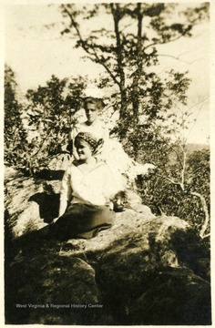 Photograph of Maggie and Helen Ballard sitting on rocks on a postcard.