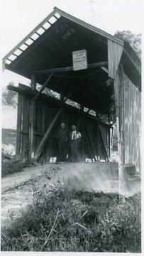 View of two men standing at entrance of bridge.