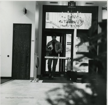 Man walking through entrance door of Colson Hall.