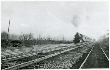 'Storms out of Alderson, towards Hinton on a winter day in 1909, pulled by an Atlantic (4-4-2) Locomotive, as a freight recedes into the background.
