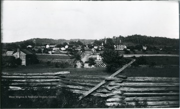 A photograph of a small town, possibly Harrisville, with a wooden fence in the foreground.