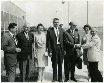 A portrait of West Virginia University faculty and their spouses, including Dr. F. Herrera (first from right), foreign languages, Mrs. Herrera (second from right), Dr. Robert Stilwell (fourth from right), Mrs. Stilwell (fifth from right), and James R. McCartney (seventh from right).