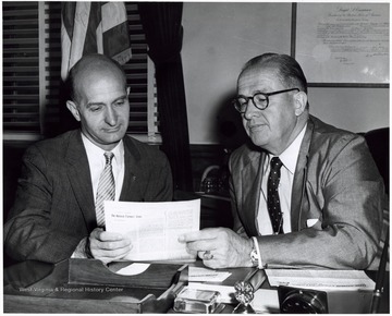 A photograph of Senator Hoblitzell (left) and Secretary Benson (right) seated at a desk studying a publication.