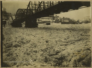 Photo of the frozen river under a bridge.