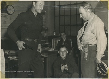 Starret, left, and Ewing, right, pose in a pretend "face-off" with their pistols. Starret starred in western films while Ewing ran the Ritze Theatre. The two men in the background are unidentified. 