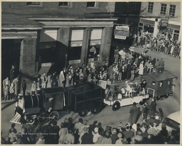 A crowd gathers on the sidewalks as a float in the parade travels through the corner of Ballengee Street and 2nd Avenue. 
