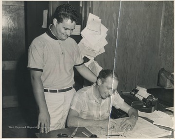 Weaver, right, signing a check to become the first member of the boosters club. This check, which appeared in The Hinton Daily News, caused 500 additional members and $1,500 to be raised by Jack Ball, pictured on the left. Ball became the first President of the boosters club. 