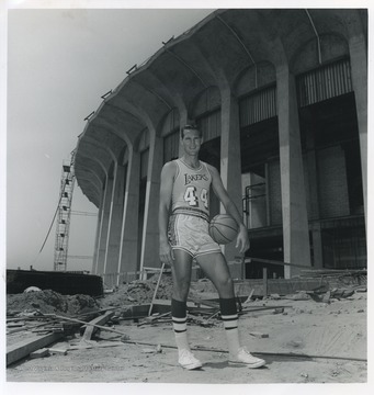 West is pictured holding a basketball on the construction site of the L.A. Forum.  He played for the Lakers from 1960-1974.